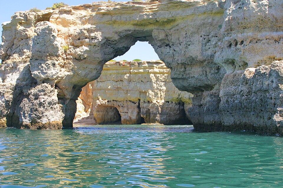 Arco de piedra natural en la playa de Albandeira, en Lagoa, Algarve, Portugal, con aguas turquesas y acantilados dorados.