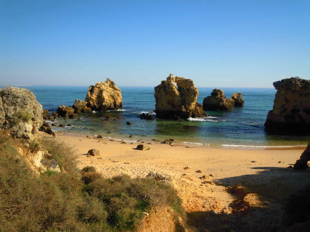 Praia dos Arrifes en Albufeira, Algarve, Portugal - pequeña playa aislada con acantilados dorados, arcos de roca y agua atlántica turquesa.