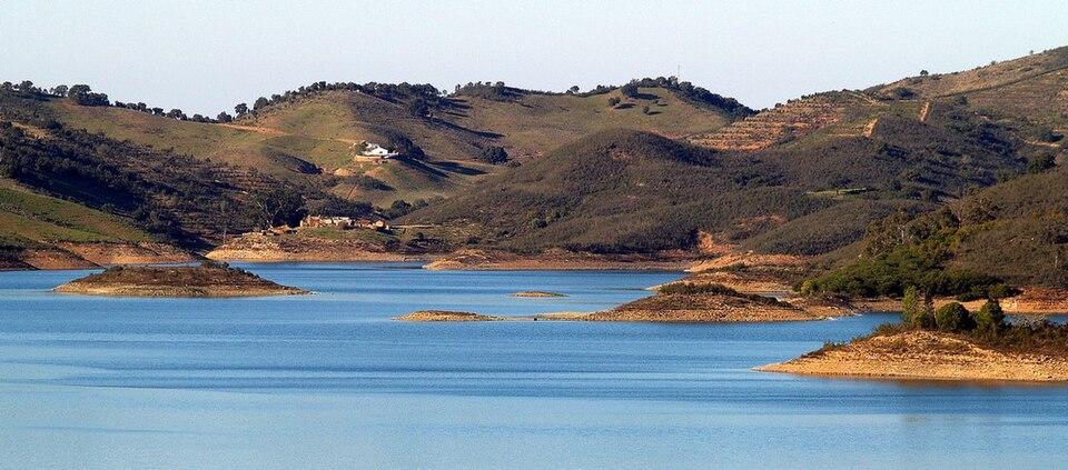 Barragem de Santa Clara en Alentejo, Portugal - tranquilo lago azul rodeado de ondulantes colinas verdes y campiña.