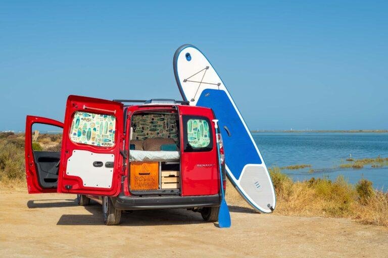 Ein Paddleboard und ein roter Campervan, geparkt an der Algarve-Küste – Ausrüstung von Ocean Camper für Paddleboard-Abenteuer in Portugal.