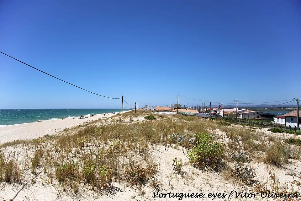 Praia de Faro med sanddyner, blått vatten och små strandhus - en avslappnad surfplats på sydkusten nära Faro.
