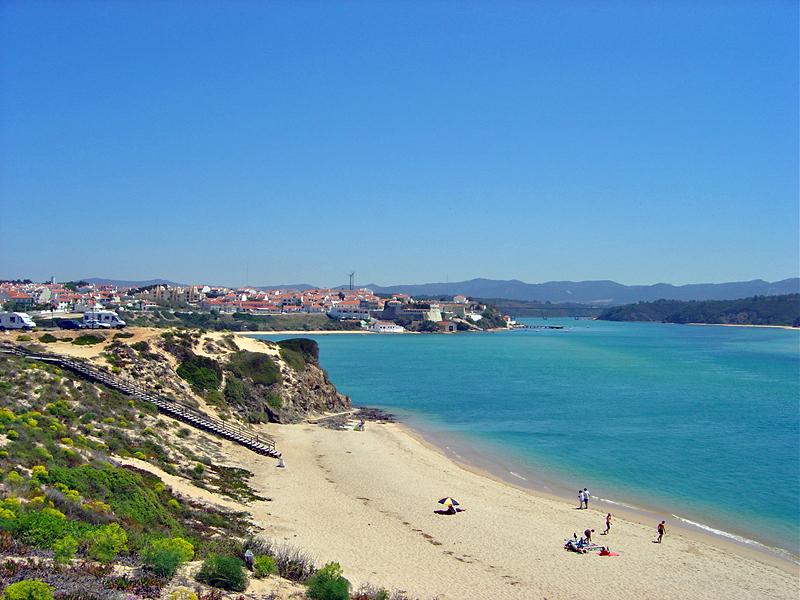Vista de Vila Nova de Milfontes, Alentejo, Portugal - playa fluvial con agua turquesa, acantilados y casas blancas en lo alto.