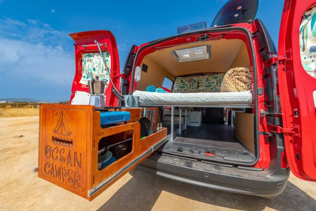 Vagabond-Mini-Campervan mit geöffneten Hecktüren, das das Bett und die ausziehbare Küche zeigt