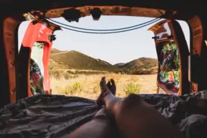 best camping apps Portugal. Relaxing inside a campervan with doors open overlooking rural hills in Portugal during a camping road trip.