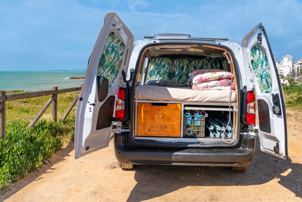 Ocean Camper Indigo campervan with open doors showing bed and kitchen setup in Algarve Portugal — perfect for outdoor adventures.