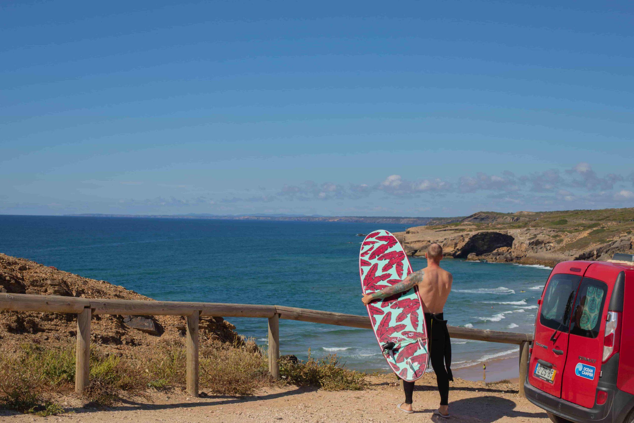 Solo travel campervan Portugal. Man about to surf in Portugal