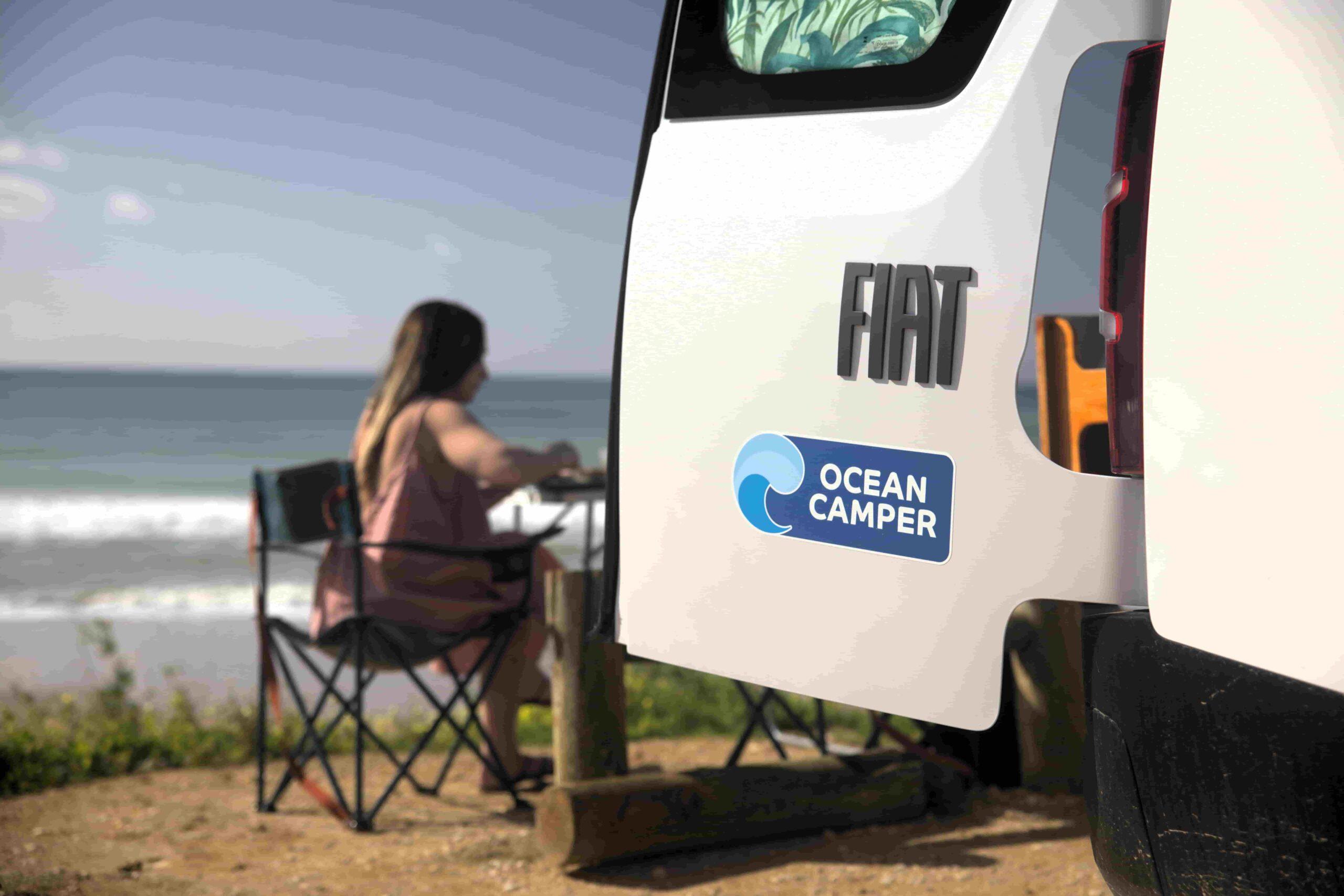 Ocean Camper van parked by the beach in Portugal with a traveler relaxing outdoors, enjoying an off-grid campervan experience.