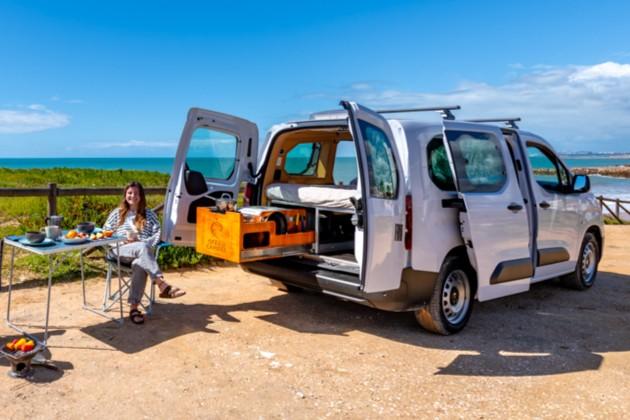 Woman enjoying breakfast by the ocean next to a compact Ocean Camper mini campervan in Algarve, Portugal.