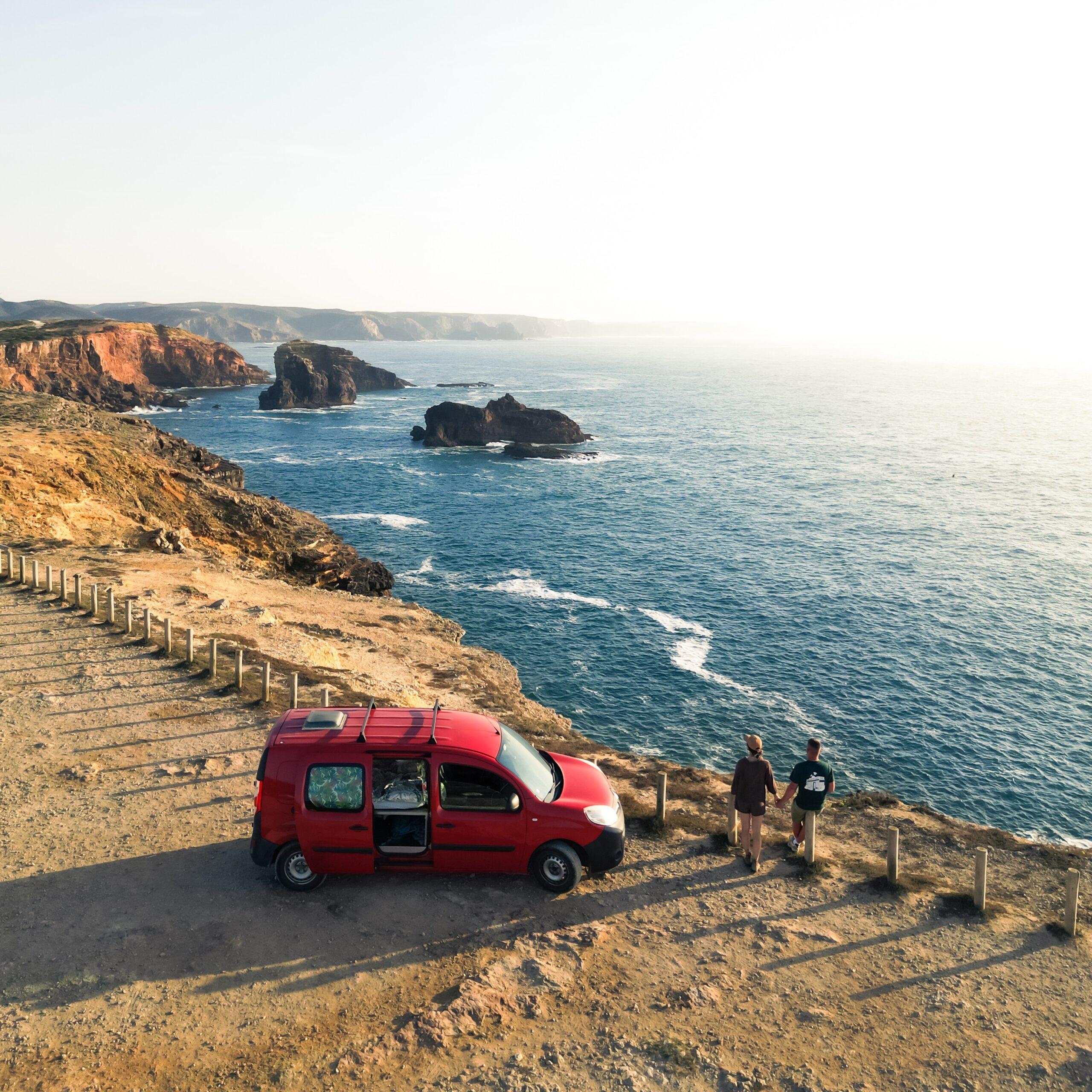 Red campervan parked on a cliff overlooking the Algarve coast — example of wild camping in Portugal.