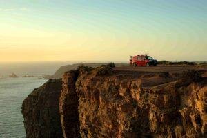 Ocean Camper van parked on Algarve cliffs at sunset, scenic view for camping and road trips in Portugal.