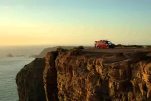 En campervan från Ocean Camper parkerad på klipporna i Algarve vid solnedgången, en vacker utsikt för camping och bilturer i Portugal.
