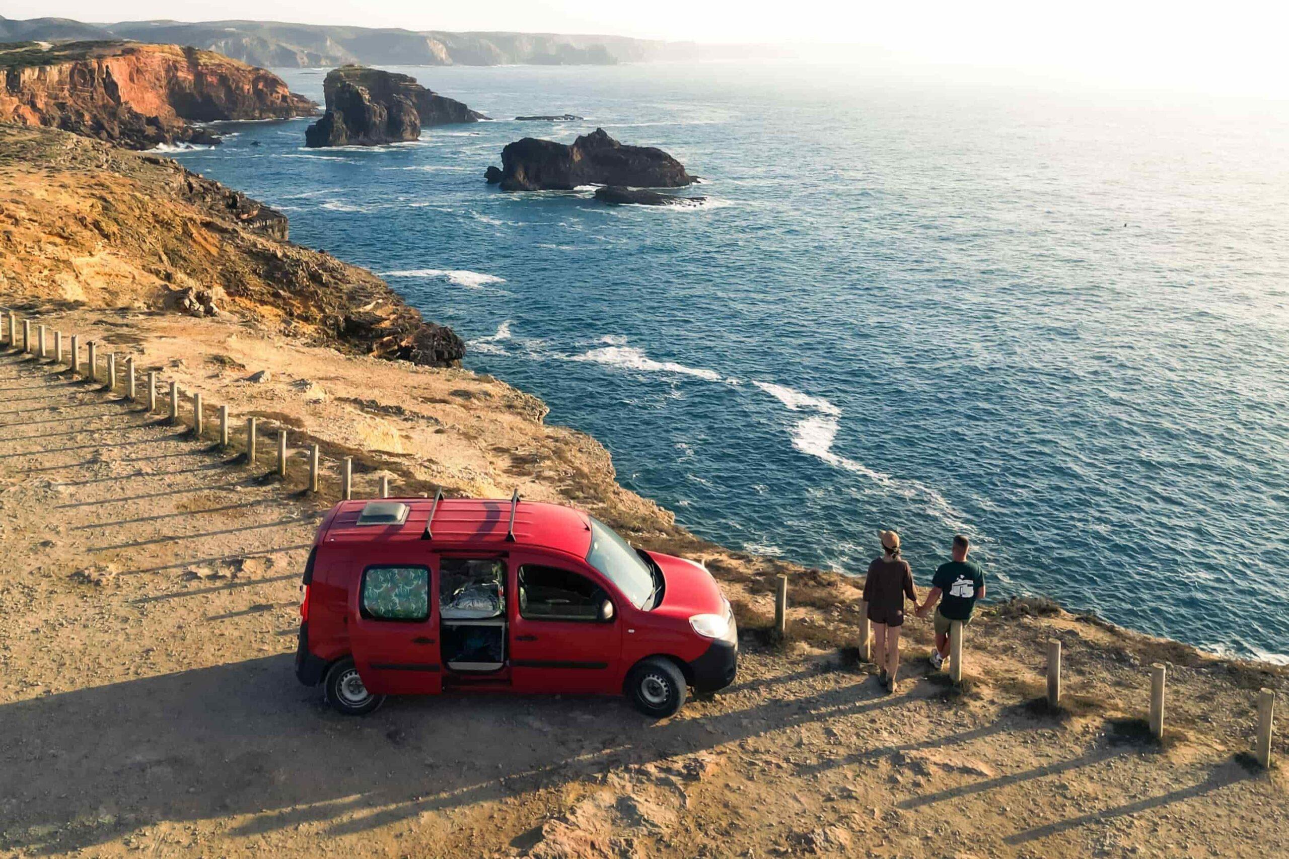Red campervan parked on a cliff overlooking the Algarve coast — example of wild camping in Portugal.