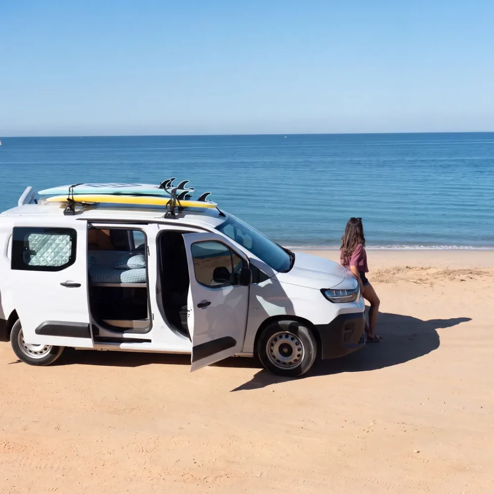 Campervan se dvěma surfy na střešním nosiči zaparkovaný u moře