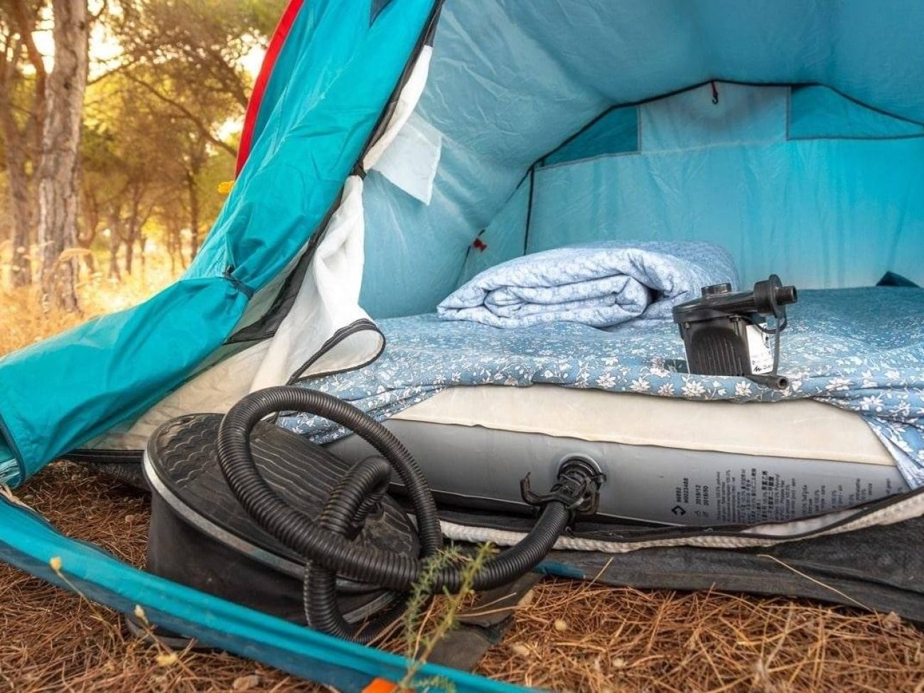 Air mattress and pump inside a blue camping tent, sleeping gear included with tent rental in Faro
